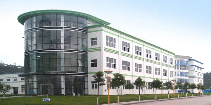 Darstellung von außen des grünen und weißen, großen und mehrstöckigen Gebäudes mit Glasfront und Baumreihe der internationalen Dr. Schulze GmbH.